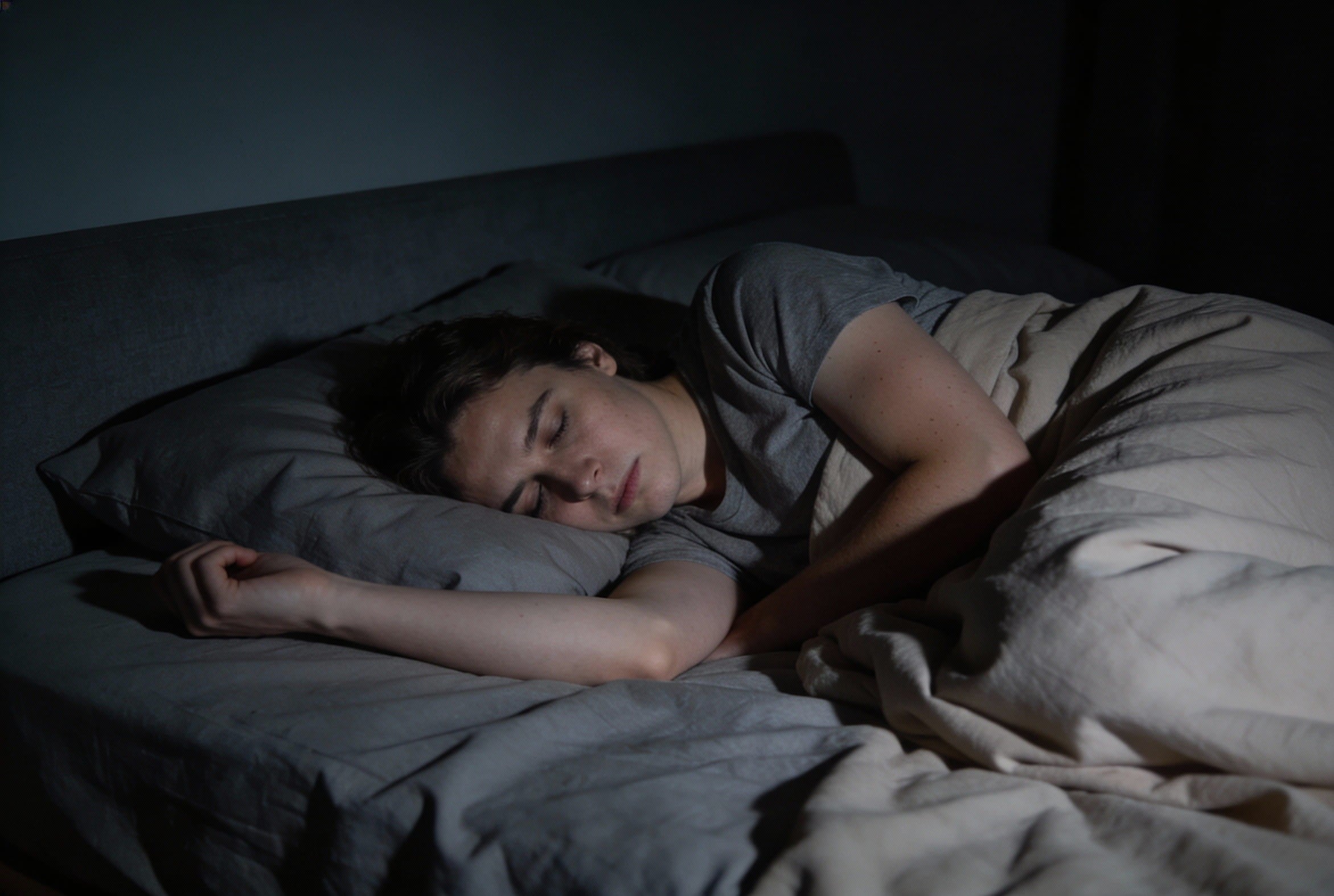 Person schläft in Seitenlage, ein Arm liegt außerhalb der Bettdecke – typische Situation für Seitenschläfer mit auskühlendem Arm.