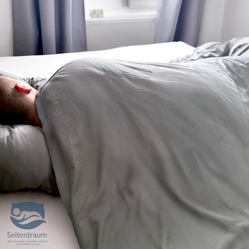 Seitenschläfer liegt unter der Seitenschläferdecke, Schulter und Oberkörper bleiben vollständig warm bedeckt.