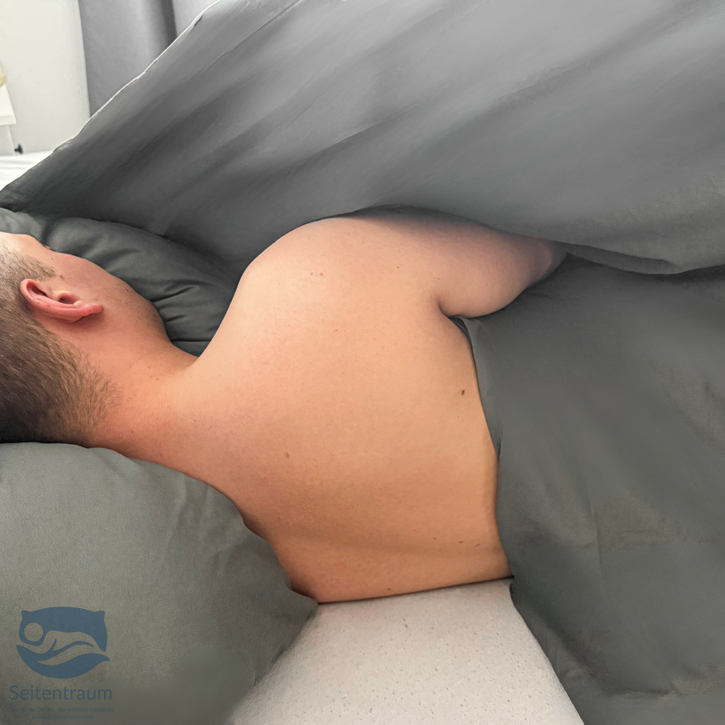Seitenschläfer liegt auf der Seite unter der grauen Seitenschläferdecke – Decke hält Schulter und Arm warm und verrutscht nicht im Schlaf.