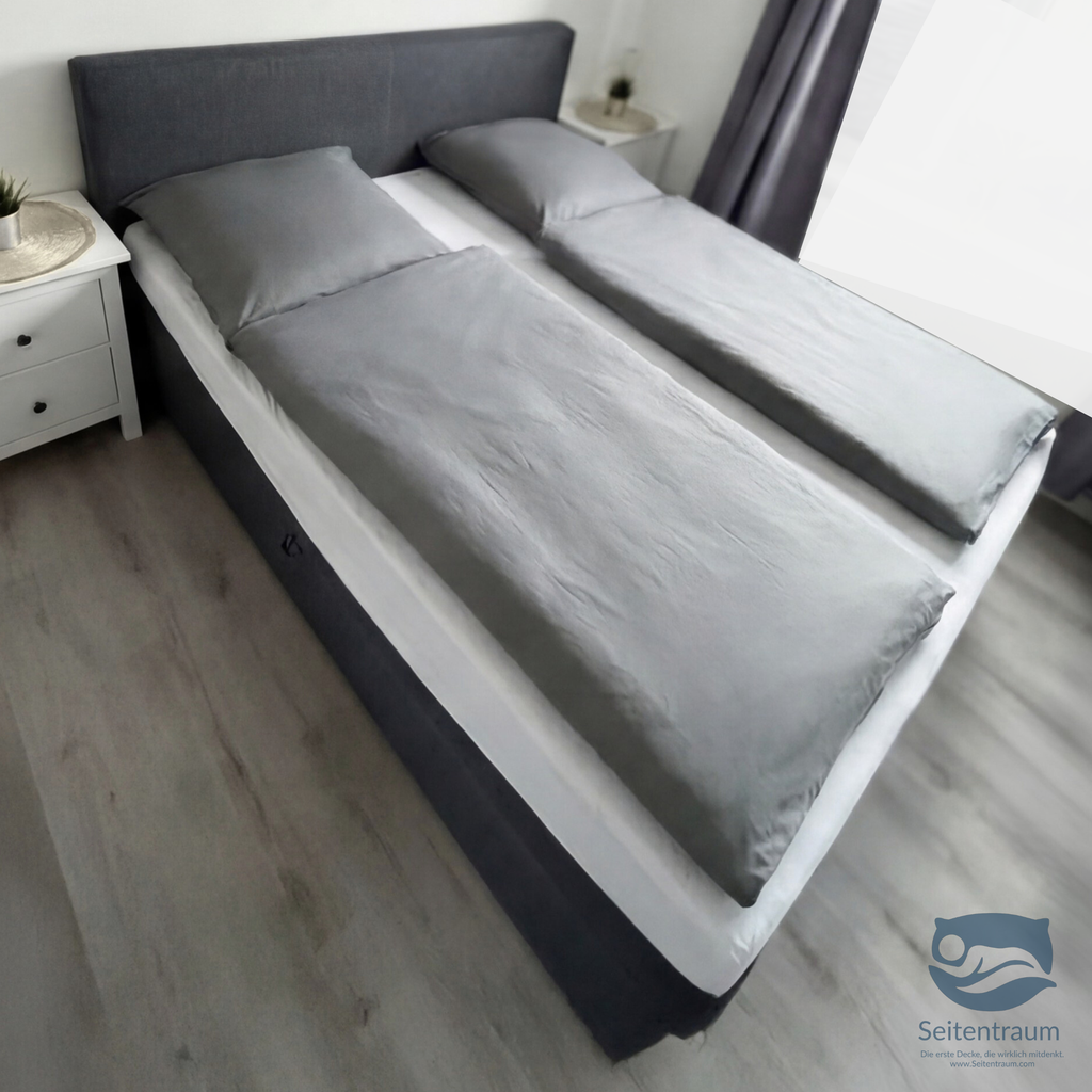 Graue Seitenschläferdecke Duo auf Doppelbett – zwei separate Decken für ruhigen Schlaf in Seitenlage ohne Verrutschen.